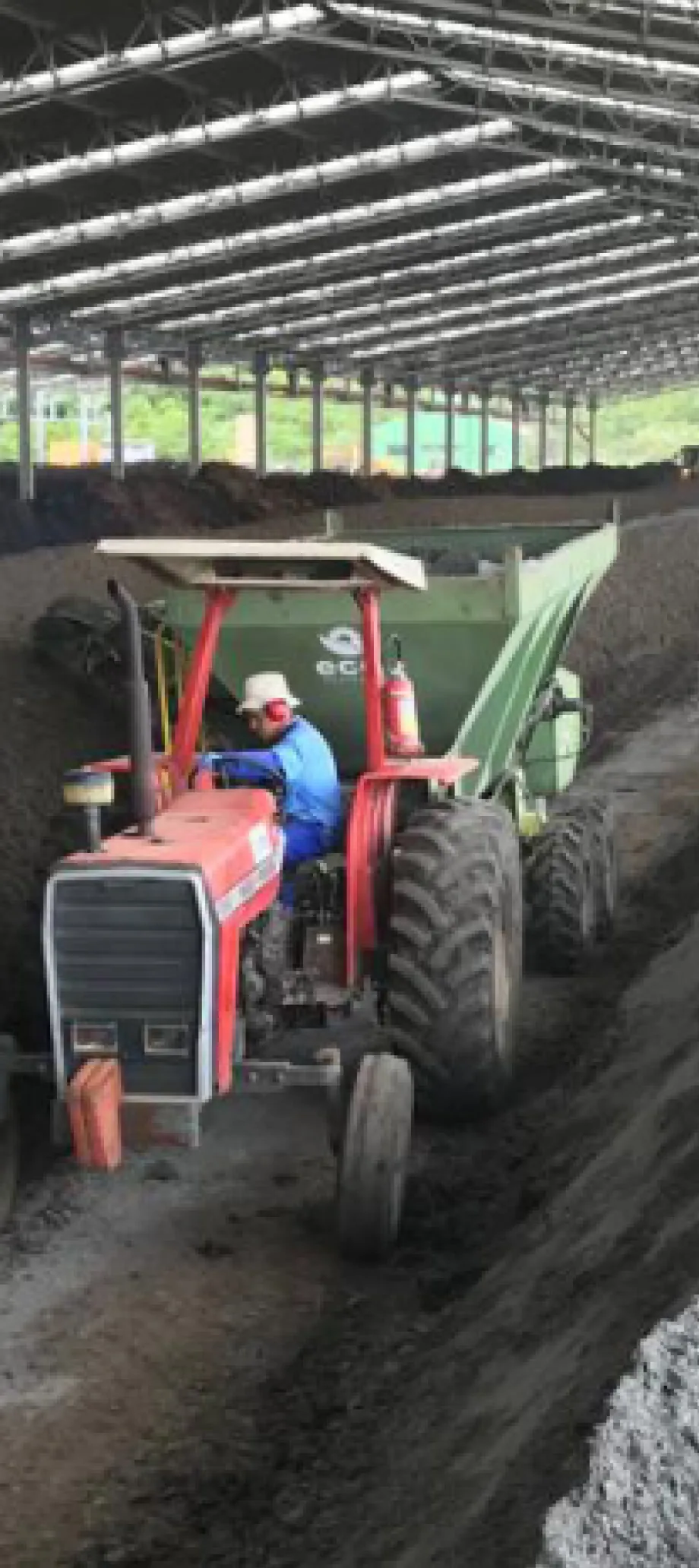 A tractor turning compost windrows at a composting yard in Brazil