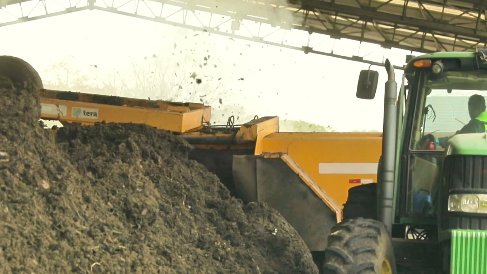 Windrow turner aerating compost inside a covered yard